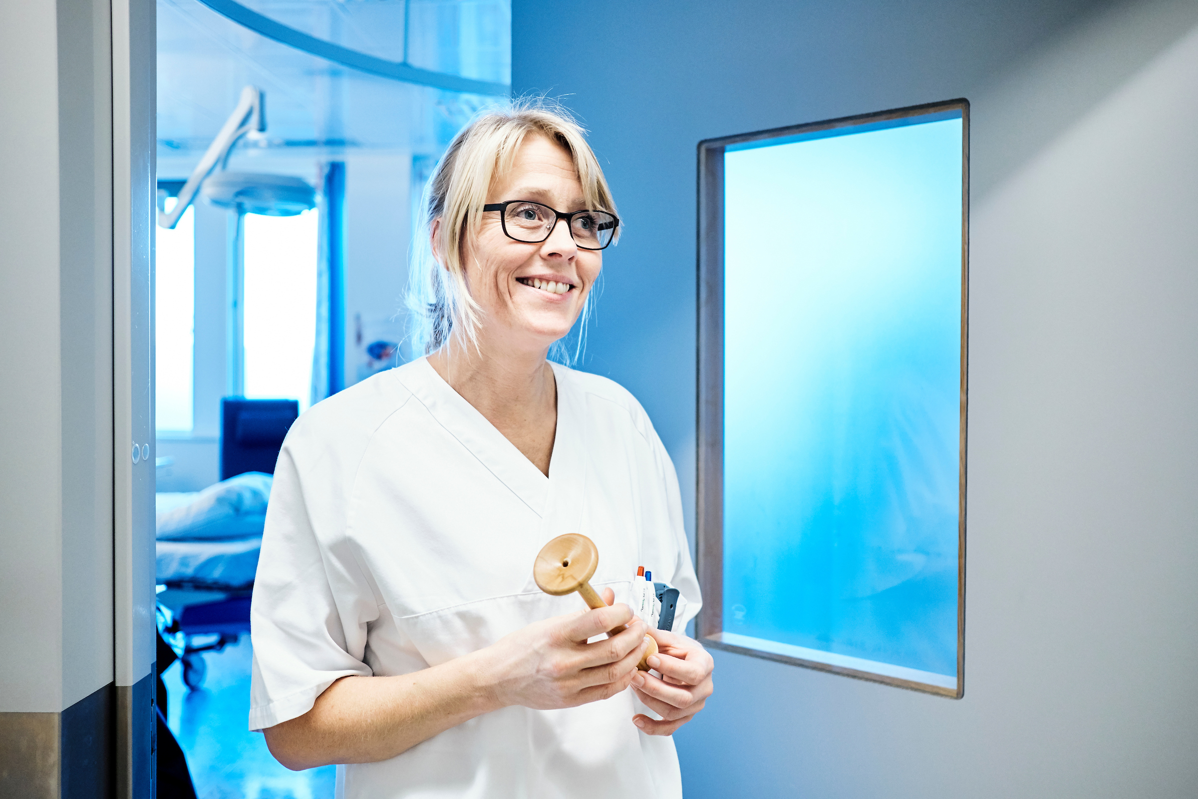 Smilende jordmor kommer ut fra et sykehusrom