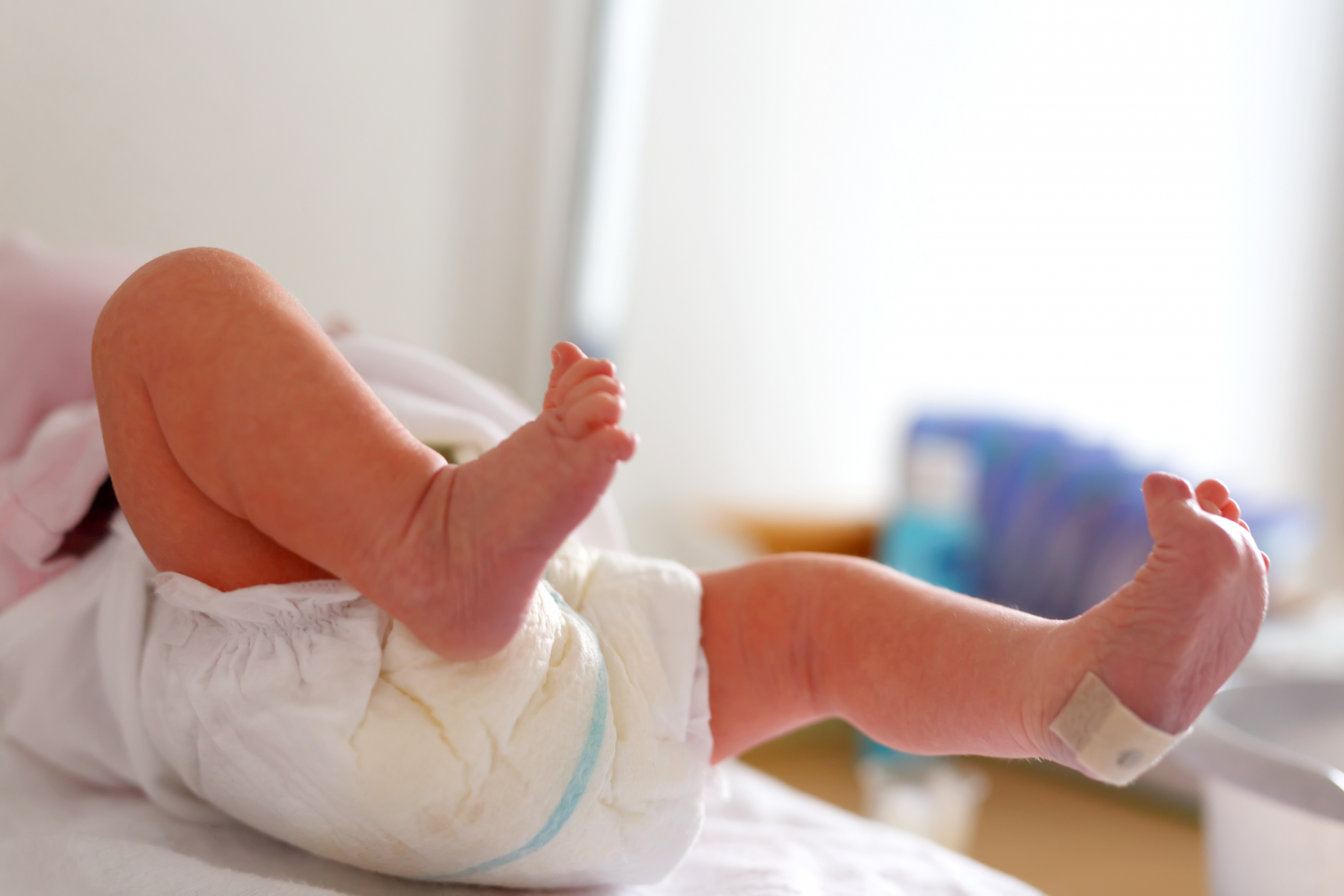 A newborn baby with a plaster on its heel