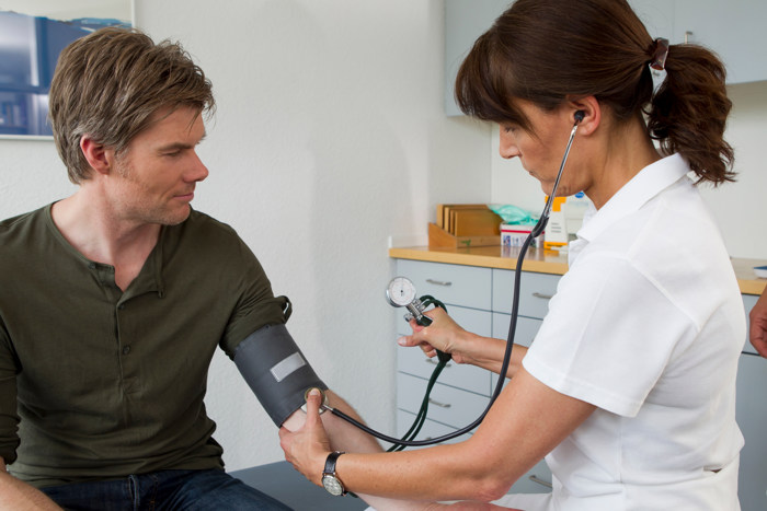 Lege utfører blodtrykksmåling på pasient. 
