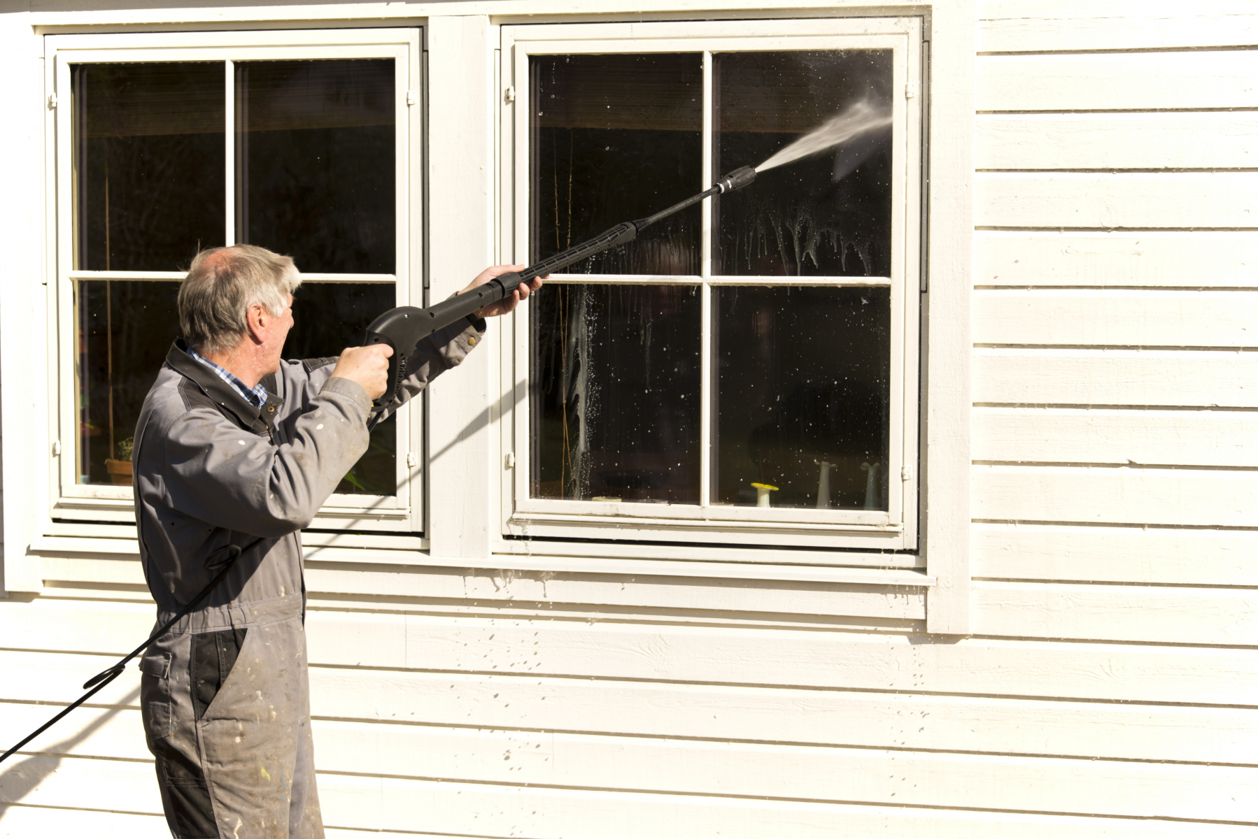 Mann vasker husvegg med høytrykkspyler