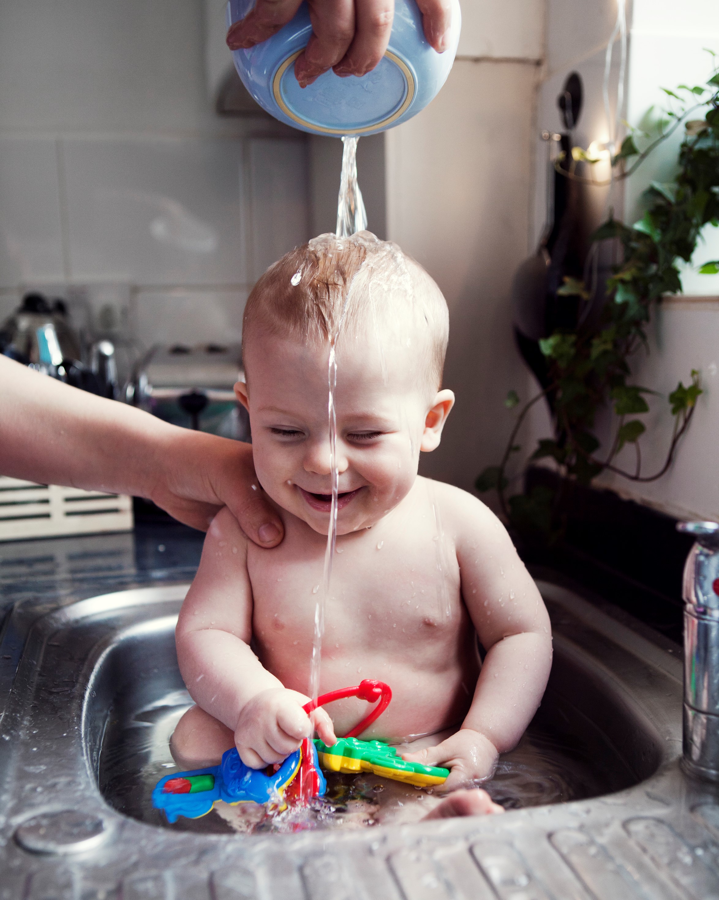 Baby som bader i kjøkkenvasken