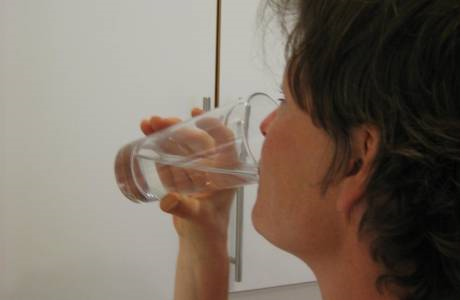 Kvinne som drikker et glass vann etter å ha svelget noe giftig