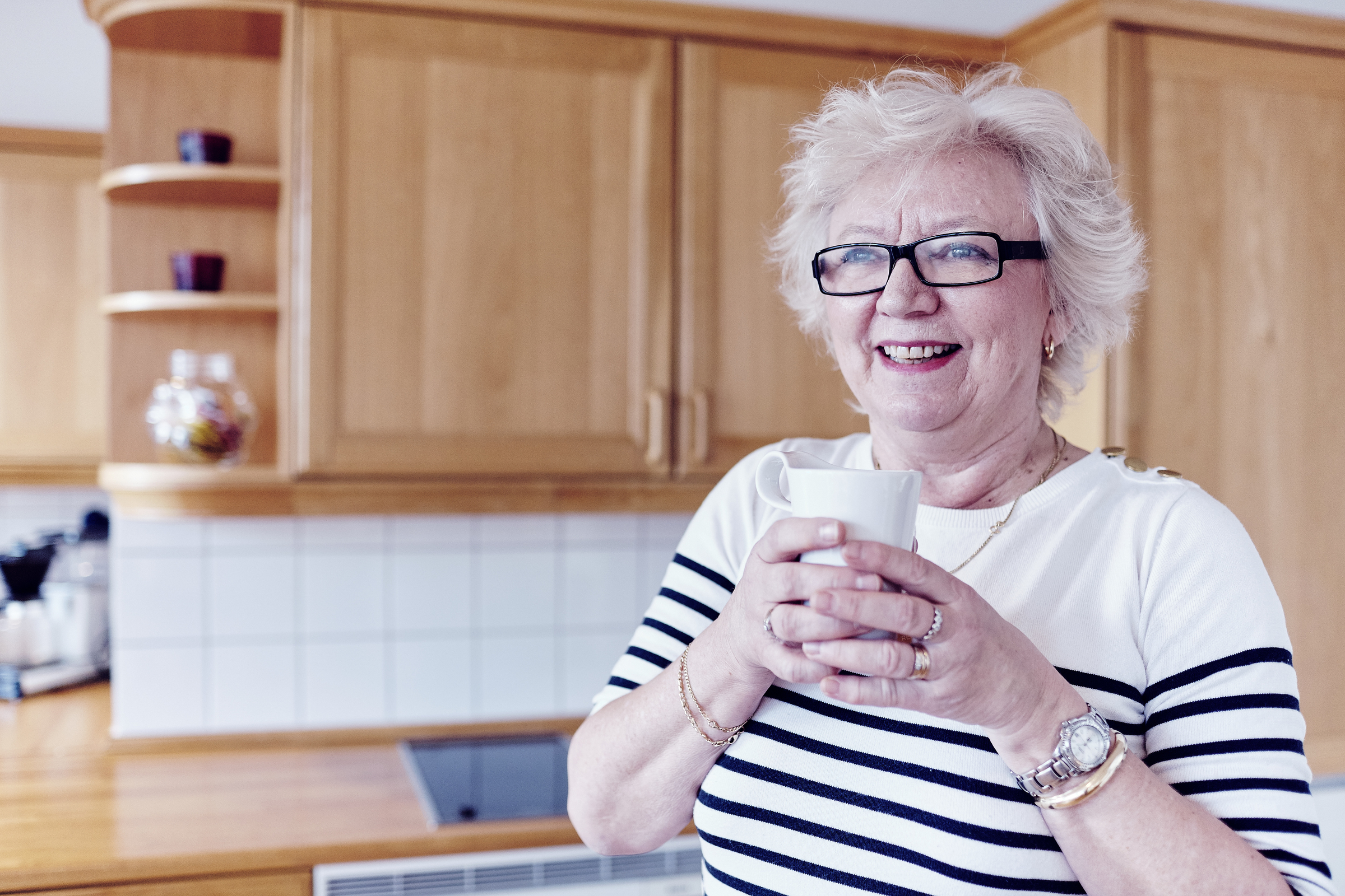 Smilende eldre kvinne på kjøkken