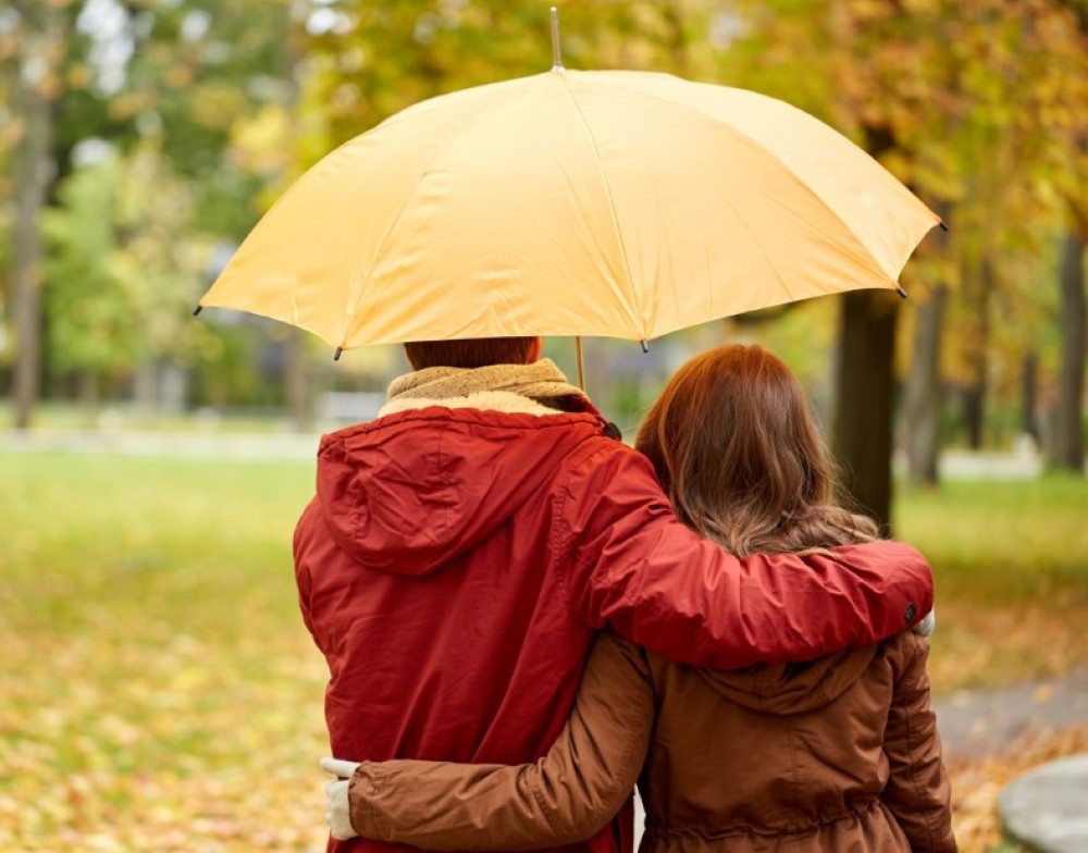Par med paraply går tur om høsten