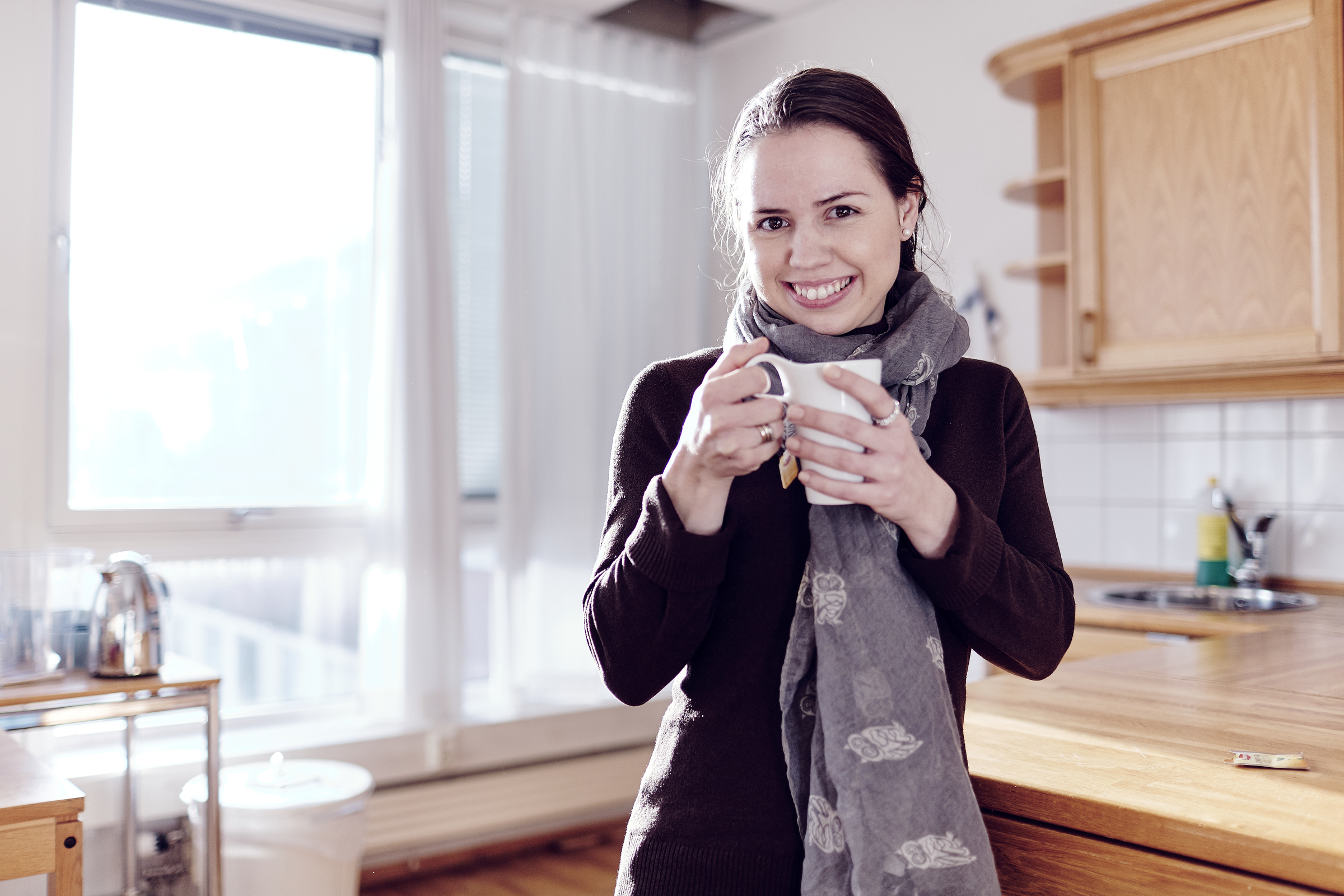Smiling young woman holding a cup in the kitchen