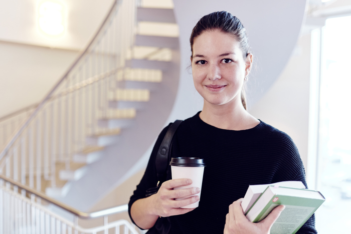 Woman carrying books and a cup