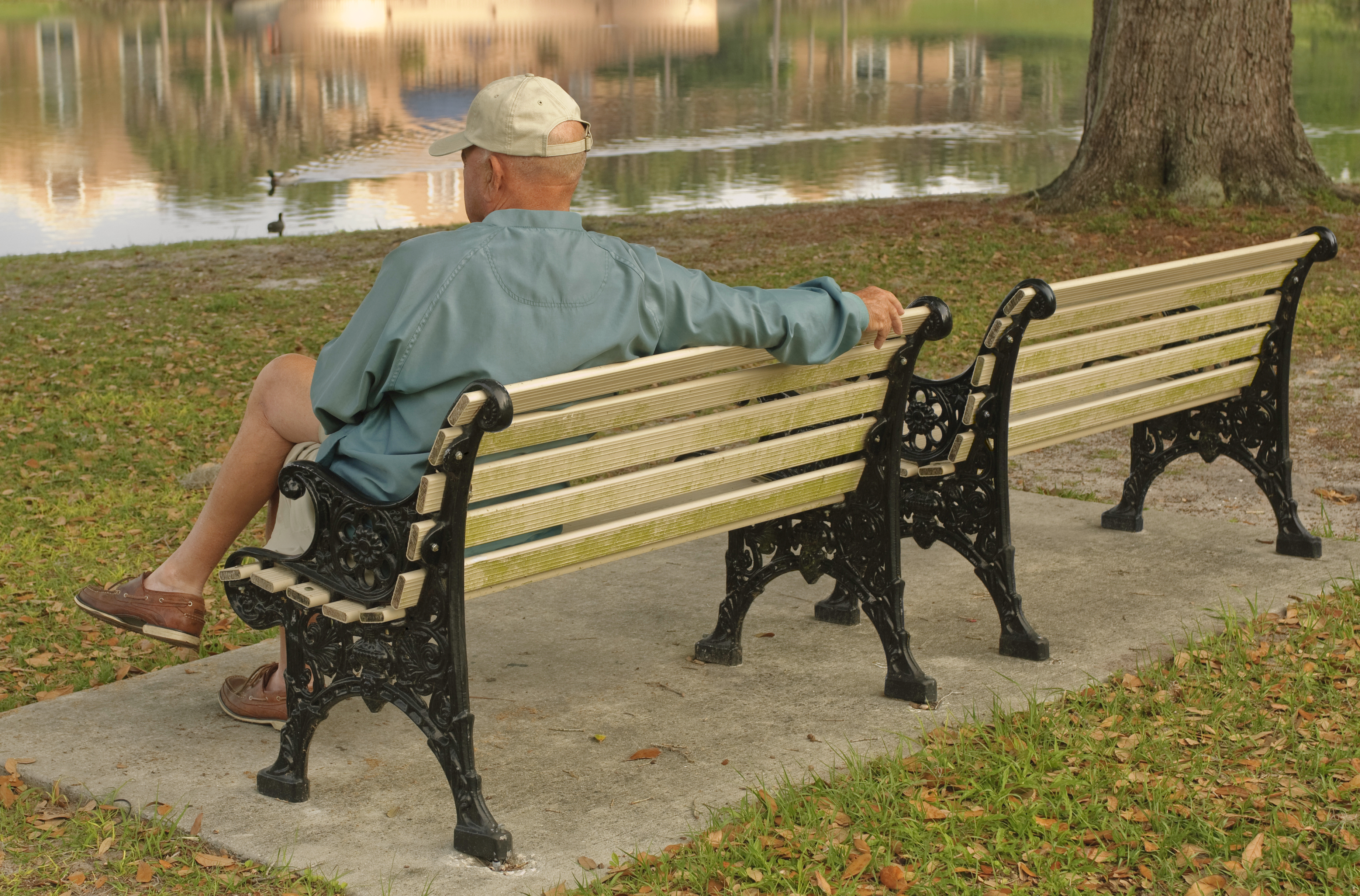 Eldre mann som sitter på en benk i parken