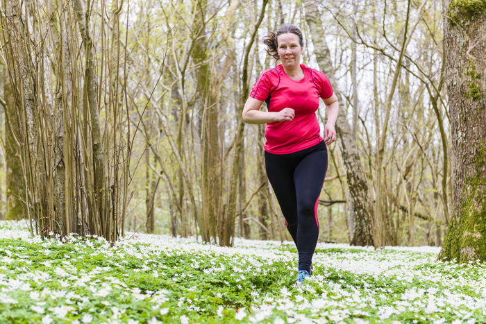 Dame som jogger i skogen