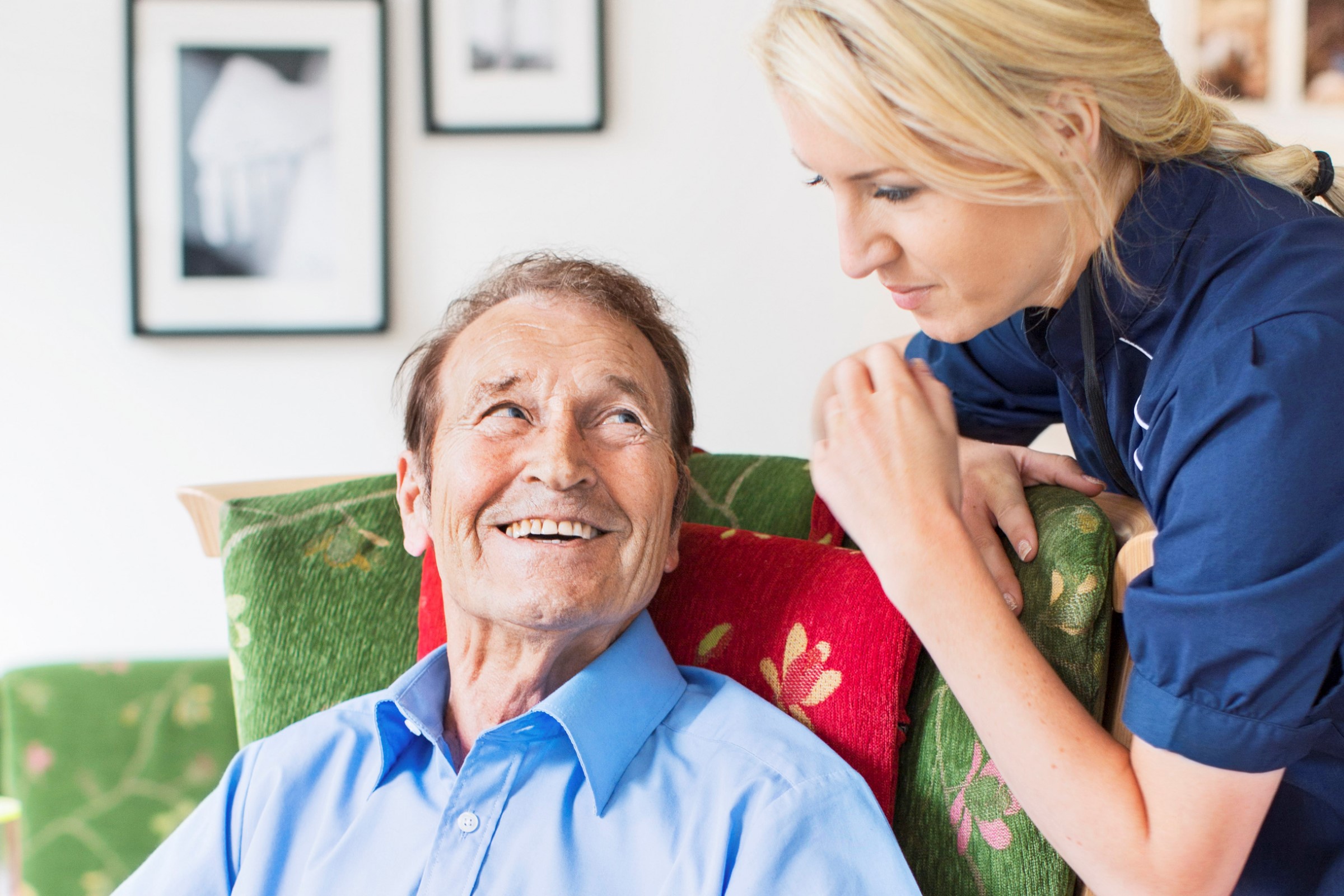 Elderly man sitting in a chair talking to a woman