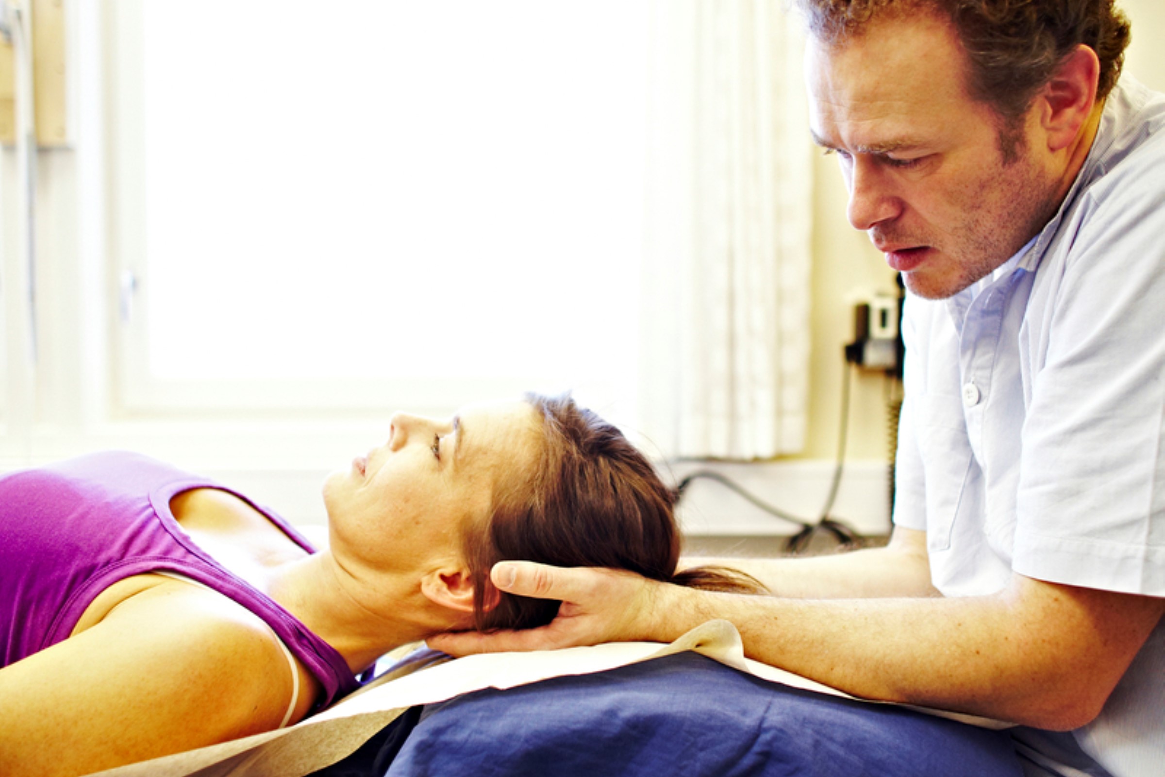 A male physiotherapist treating a woman's neck