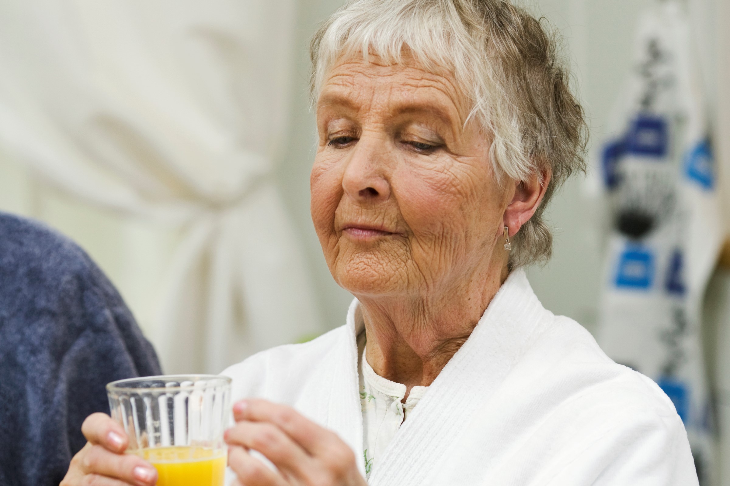 Eldre kvinne som får behandling holder et glass juice.