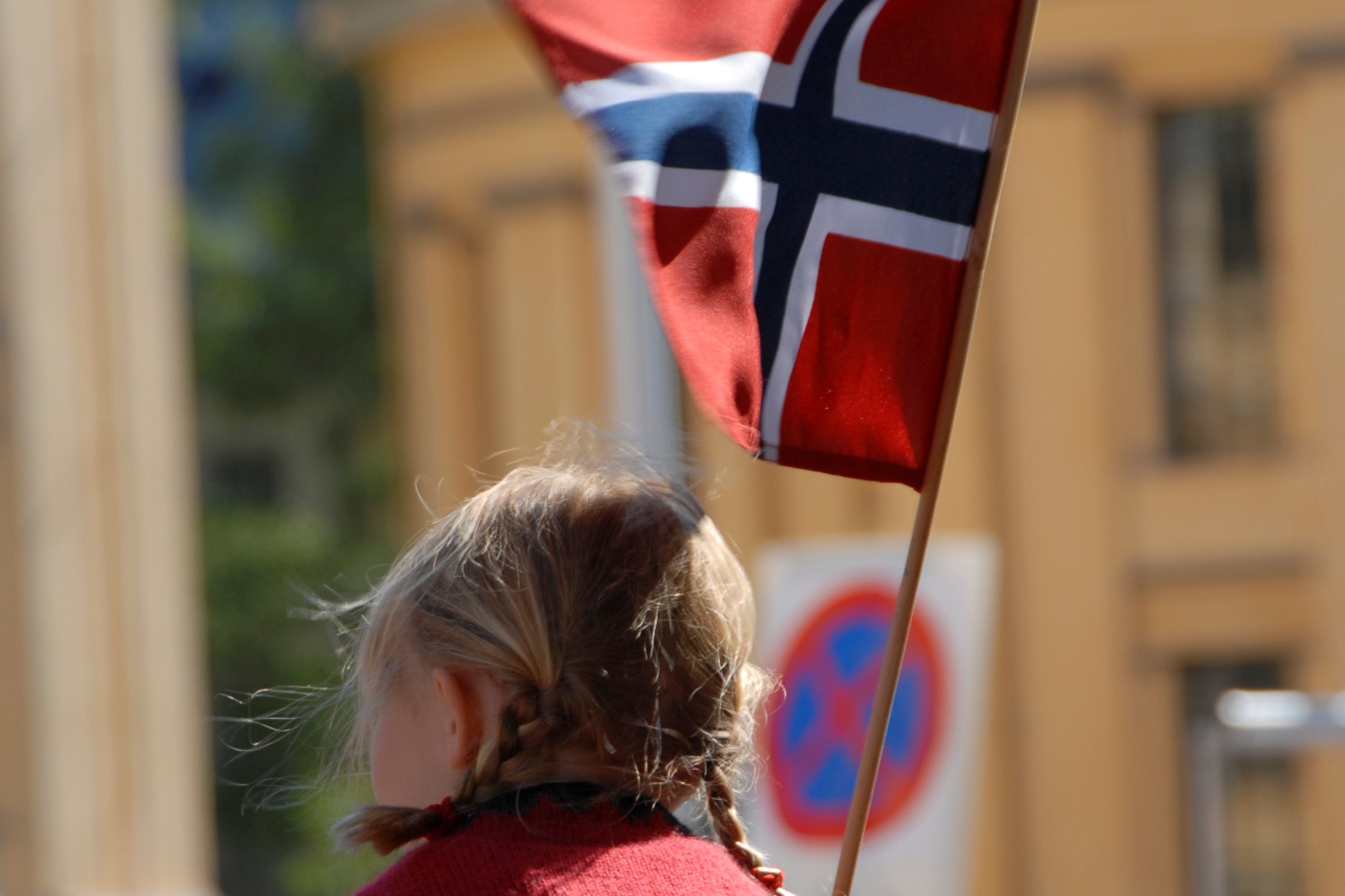Jente i bunad som bærer det norske flagget.