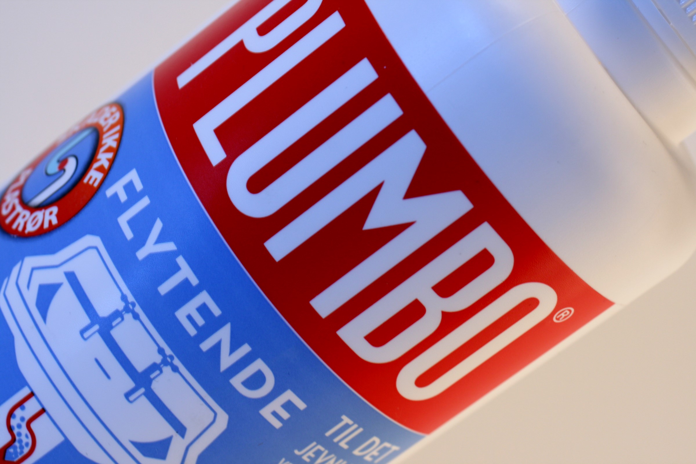 Hvit flaske med rødt merke som viser Plumbo sin logo