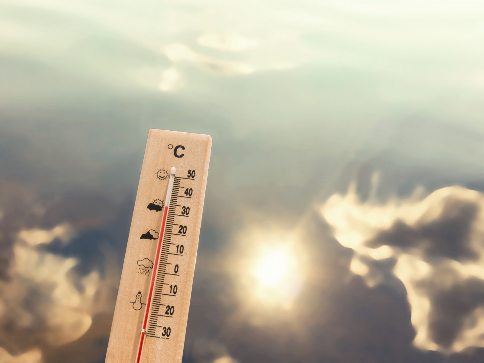 Termometer som viser 30 grader varme, med en sjøbakgrunn som refleterer sol og skyer.
