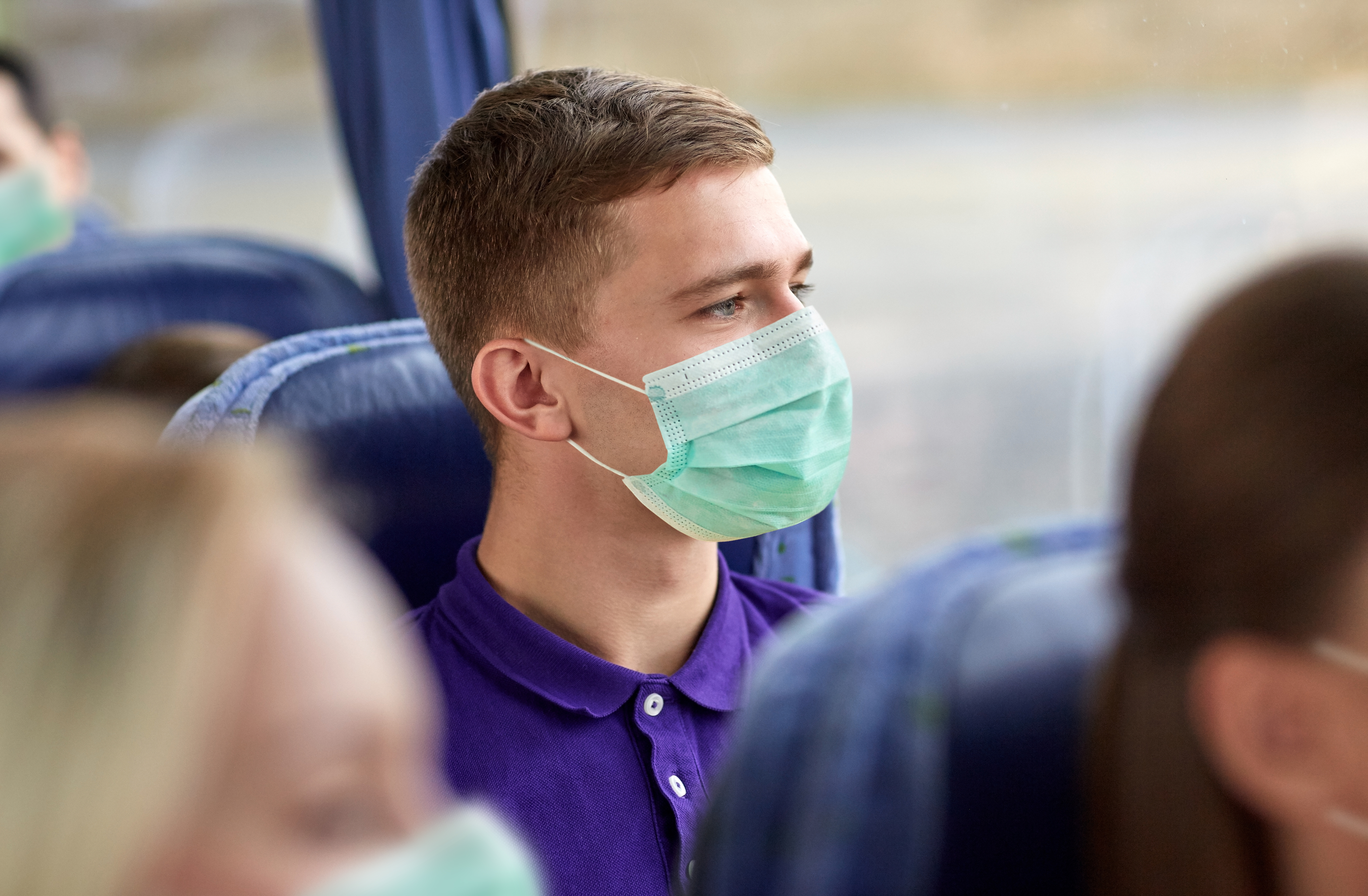 Young man on a bus wearing a face mask