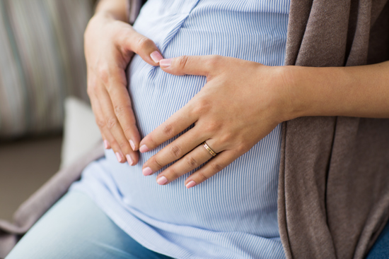 Gravid kvinne holder på magen sin