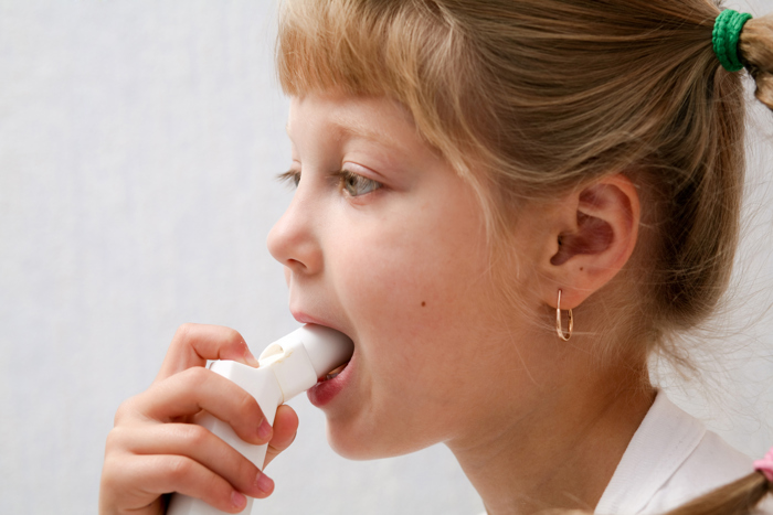 Barn viser hvordan man bruker en inhalator og holder en inhalator foran munnen.