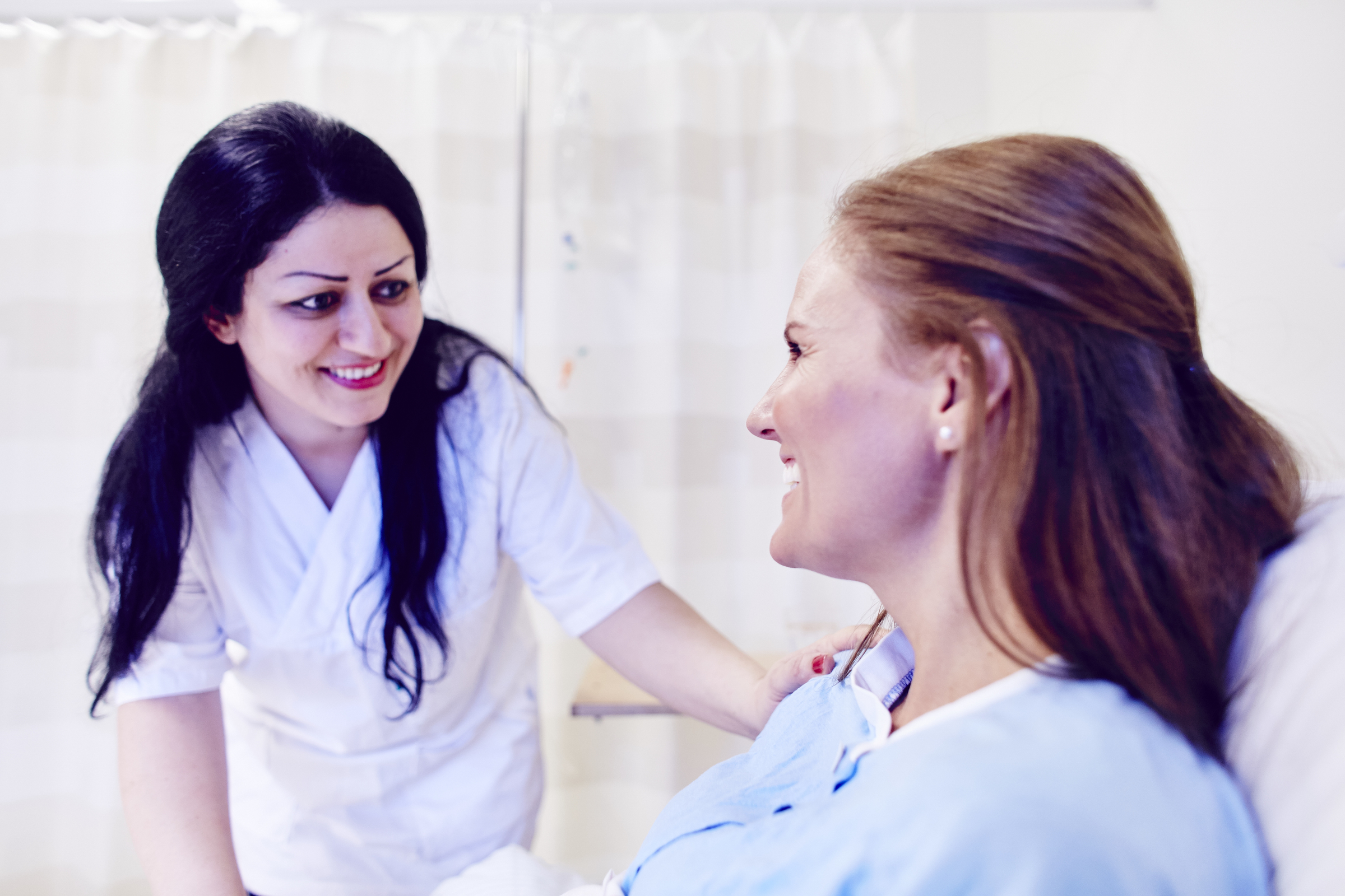 Smilende sykepleier og pasient snakker sammen