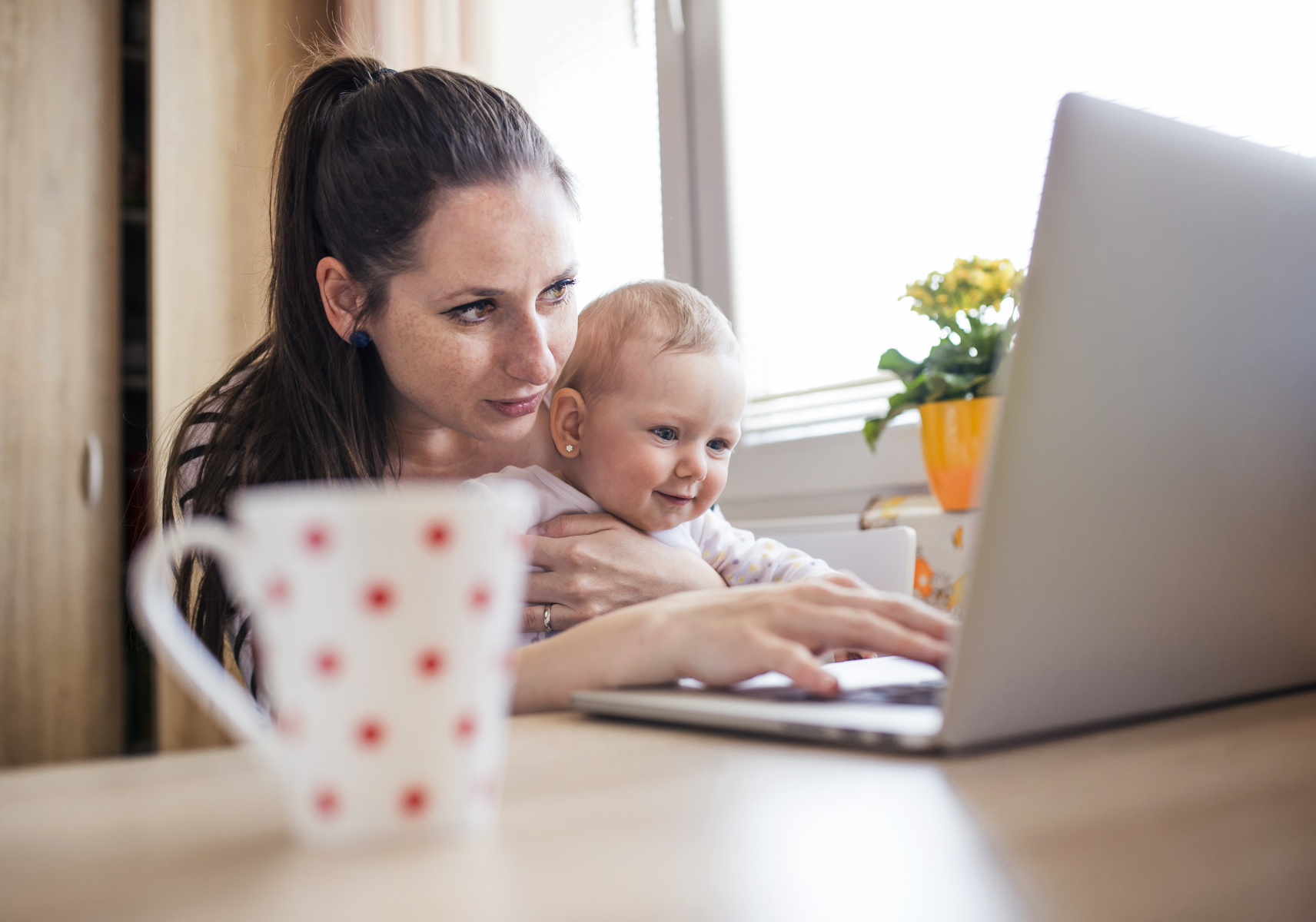 Young mother with a baby looking at a computer screen
