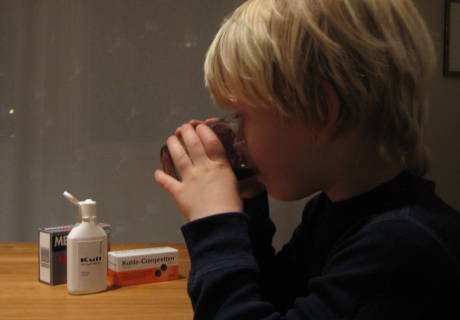 Lite barn med lys lugg som drikker medisinsk kull etter forgiftningsuhell