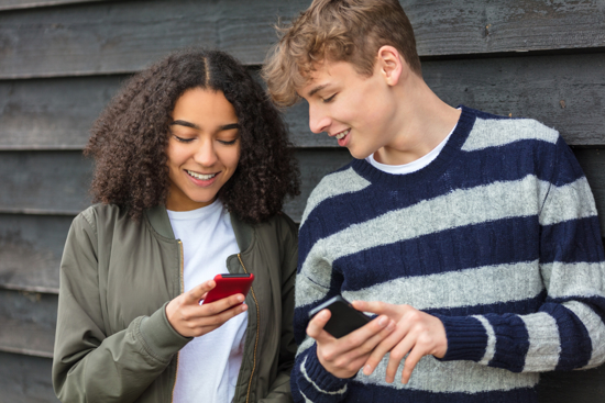 Two teenagers looking at their phones