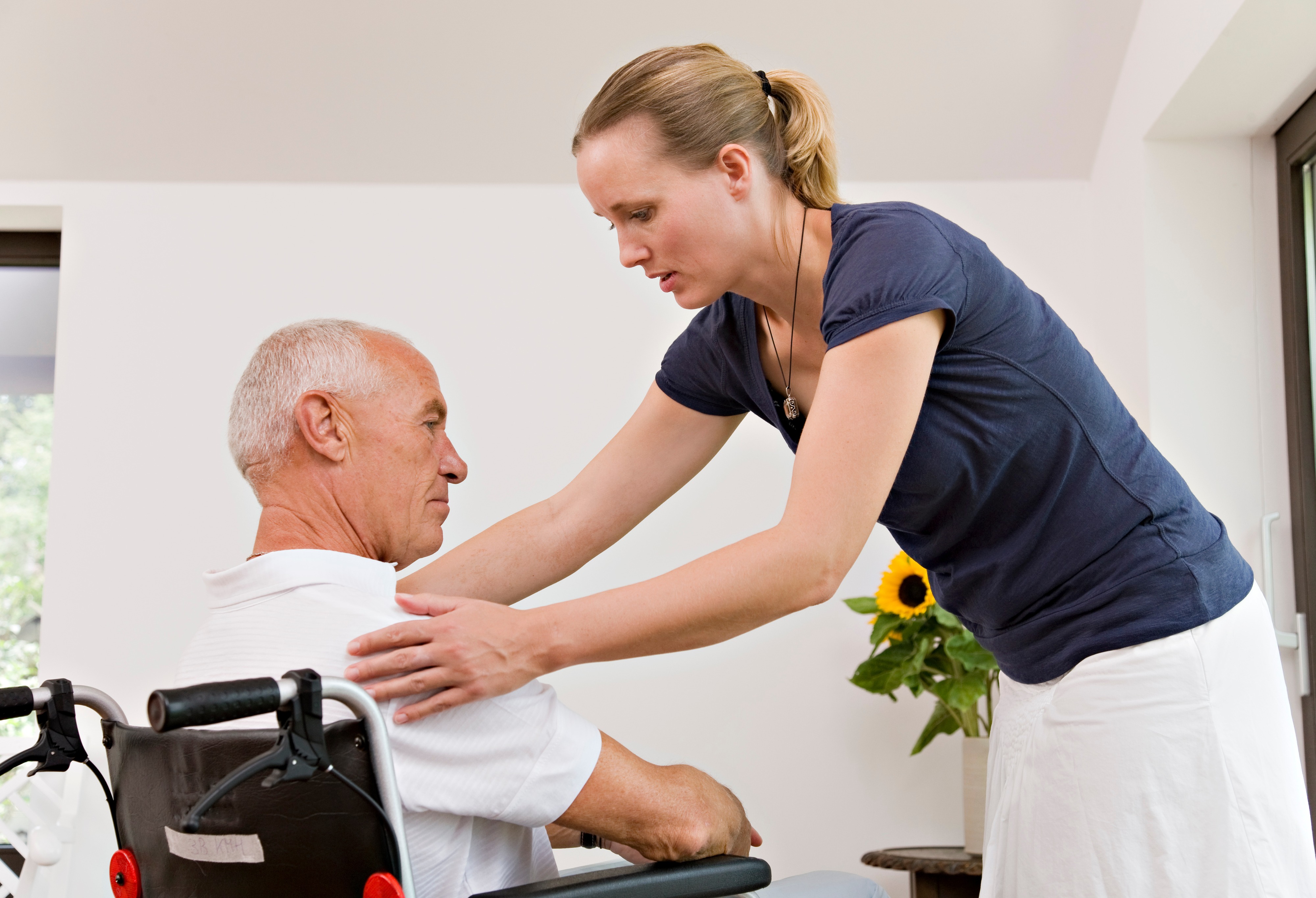 Woman helping an old man in a wheelchair
