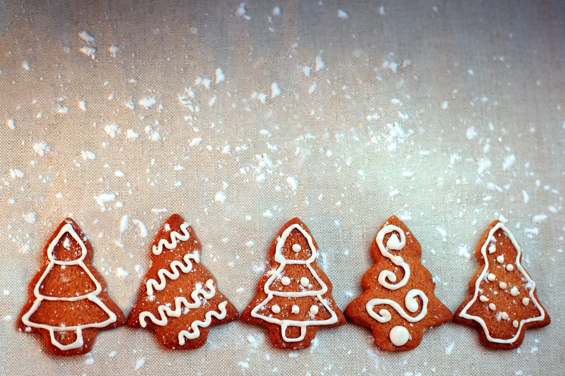 Fem pyntede pepperkaker formet som juletrær ligger på rad